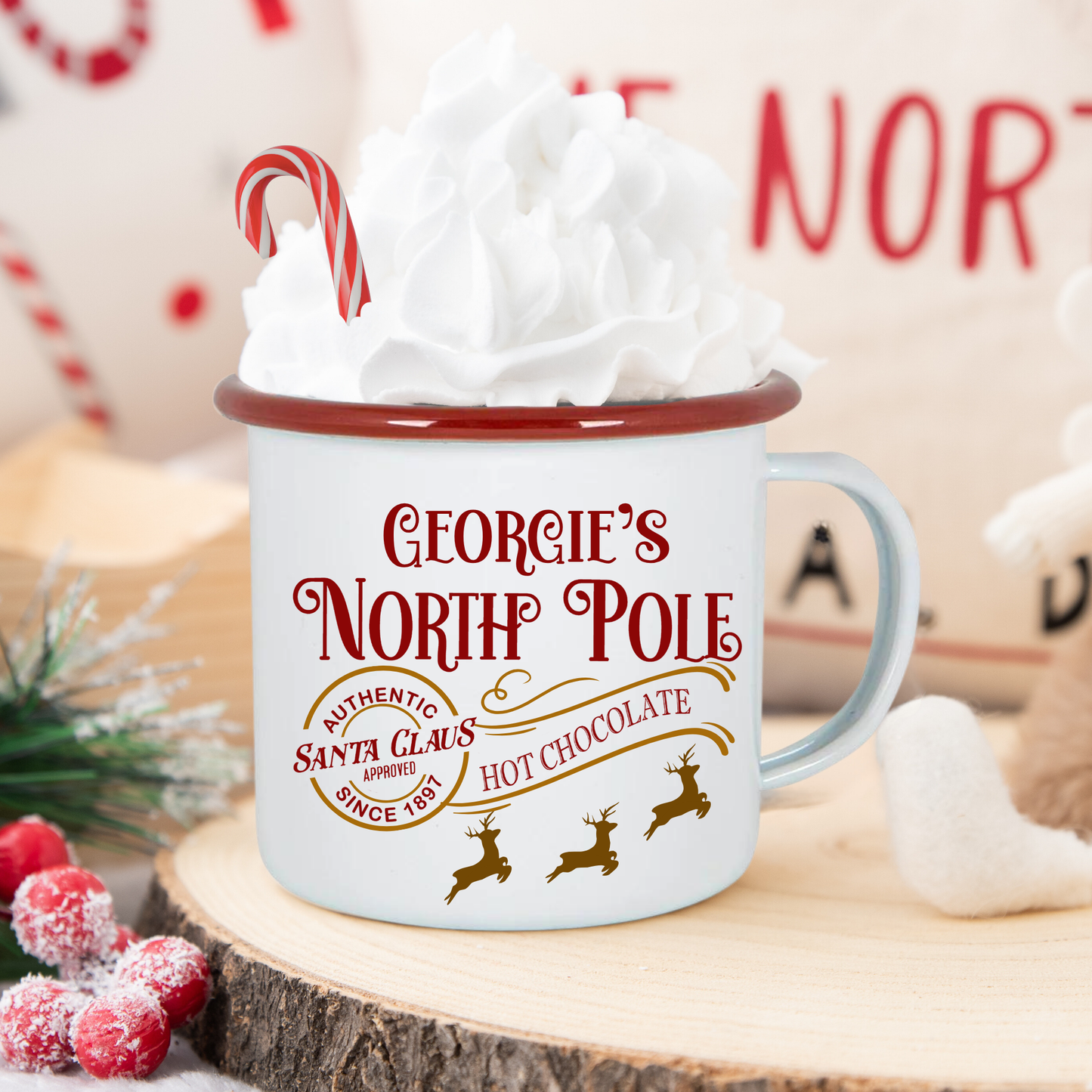 White mug with red text and design on a wooden surface with Christmas decorations.