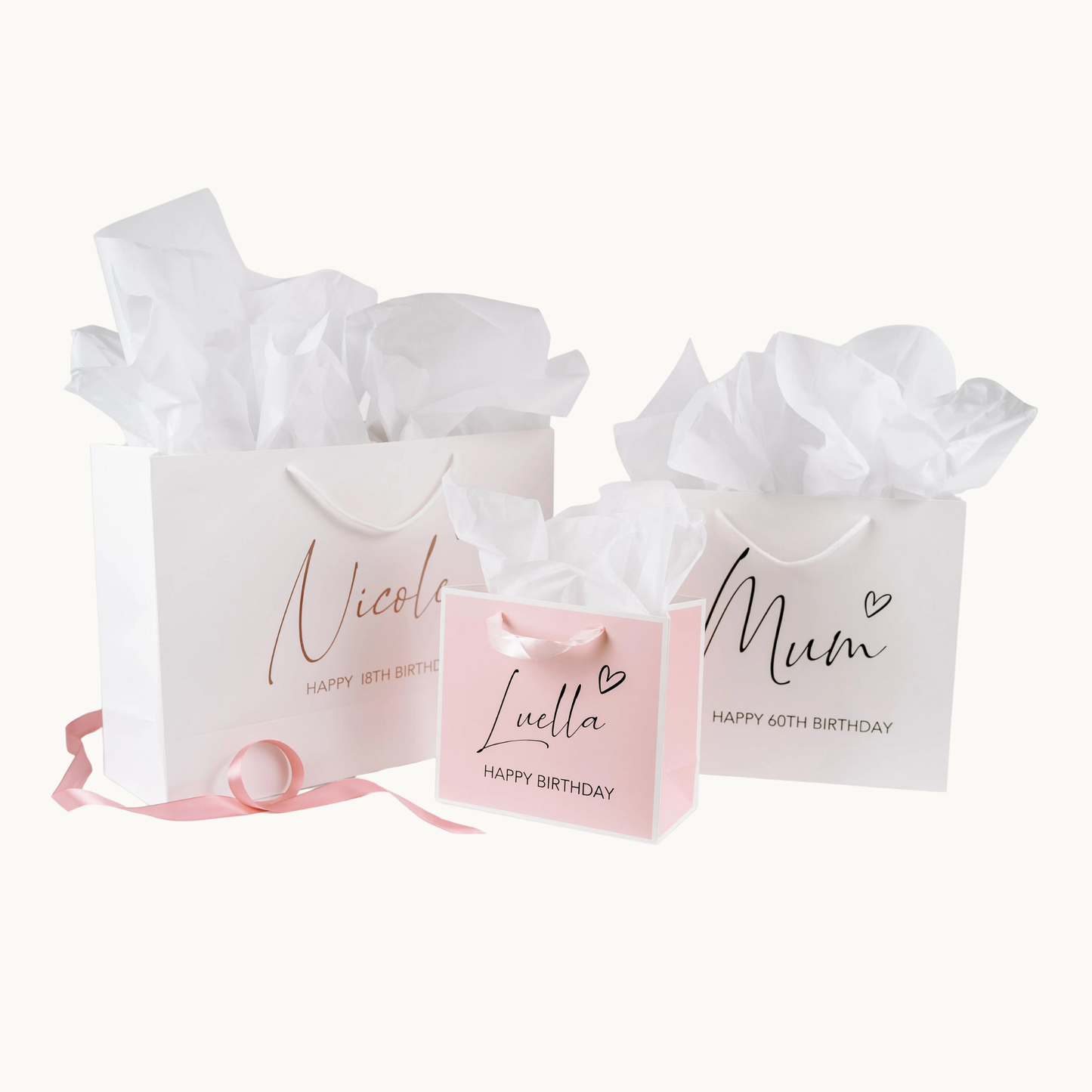 3 gift bags, 2 white and 1 pink, printed with personalised happy birthday and names, with a heart symbol on white background