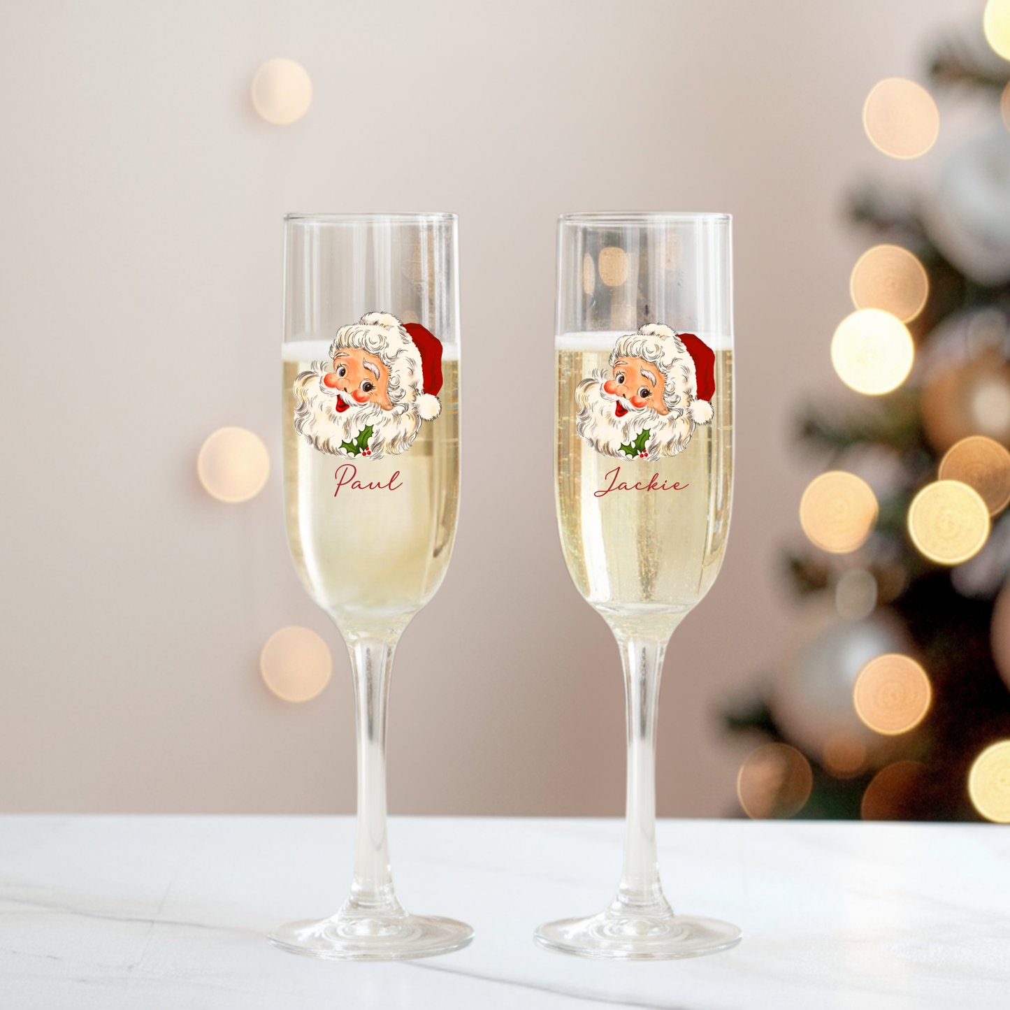 Two champagne flutes with Santa Claus illustrations and personalized names against a festive background.