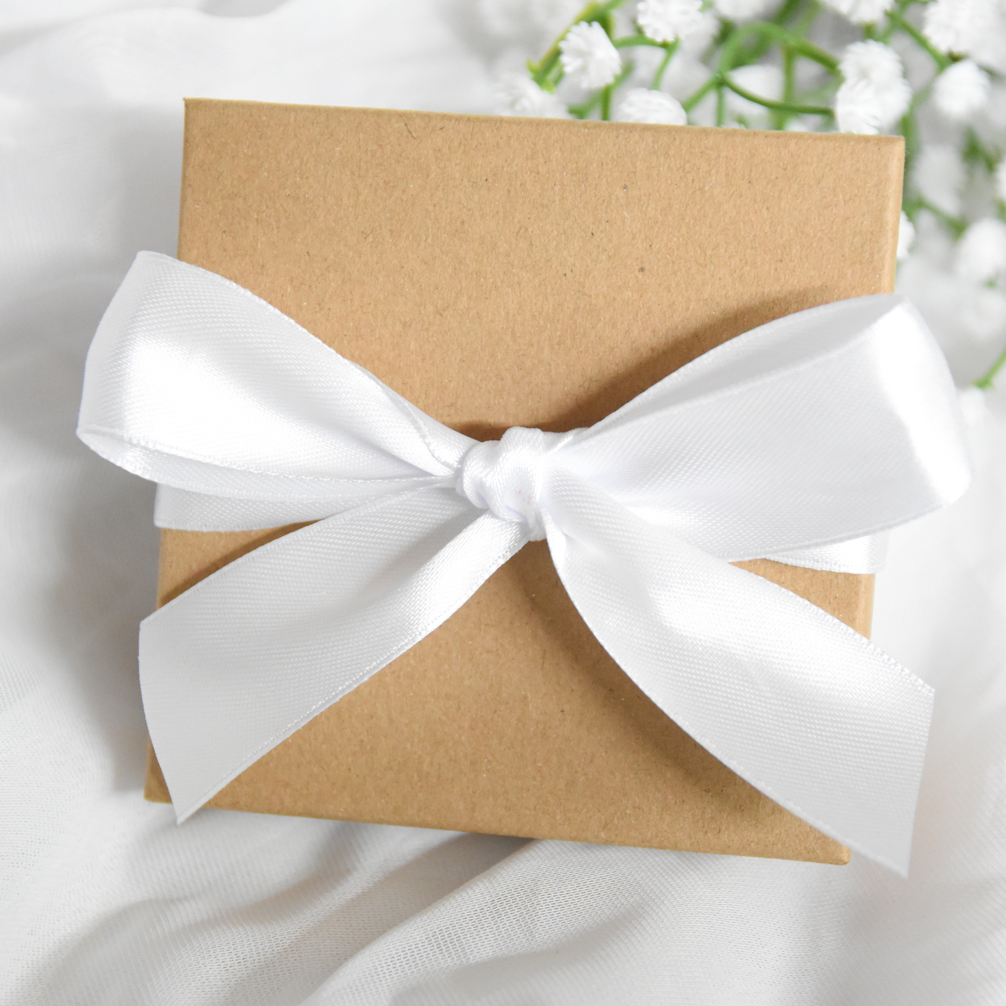 Kraft paper gift box with a white ribbon on a light background