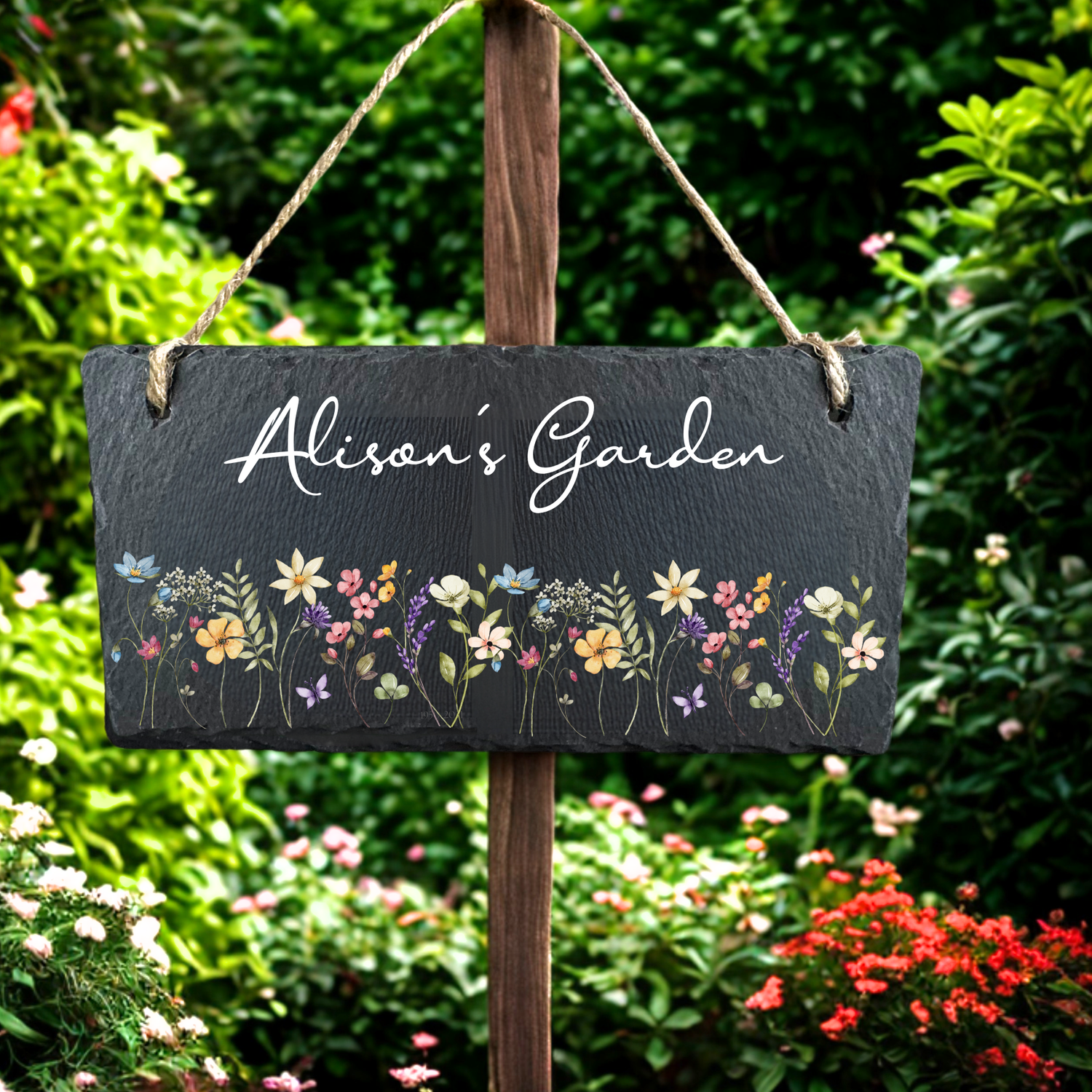 Personalised garden slate sign displayed in a garden with plants and flowers