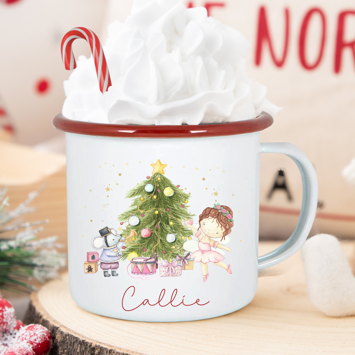 Christmas-themed mug with a design of a tree, children, and presents, filled with hot chocolate and whipped cream.