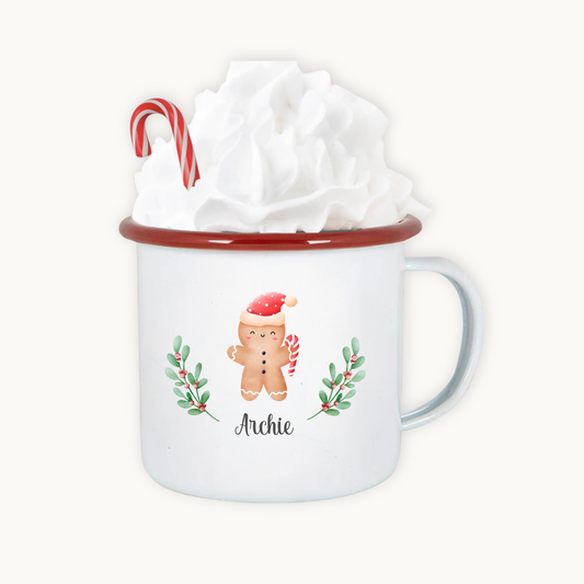 White mug with red rim featuring a gingerbread man design, candy cane, and holly leaves, with a gift wrapped inside.