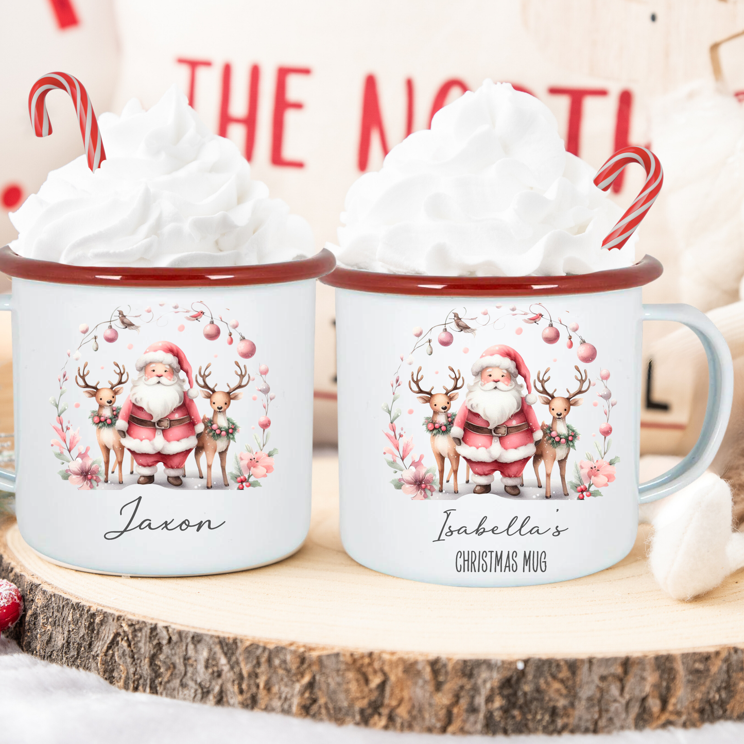 Two Christmas-themed mugs with Santa Claus and reindeer design on a wooden surface.