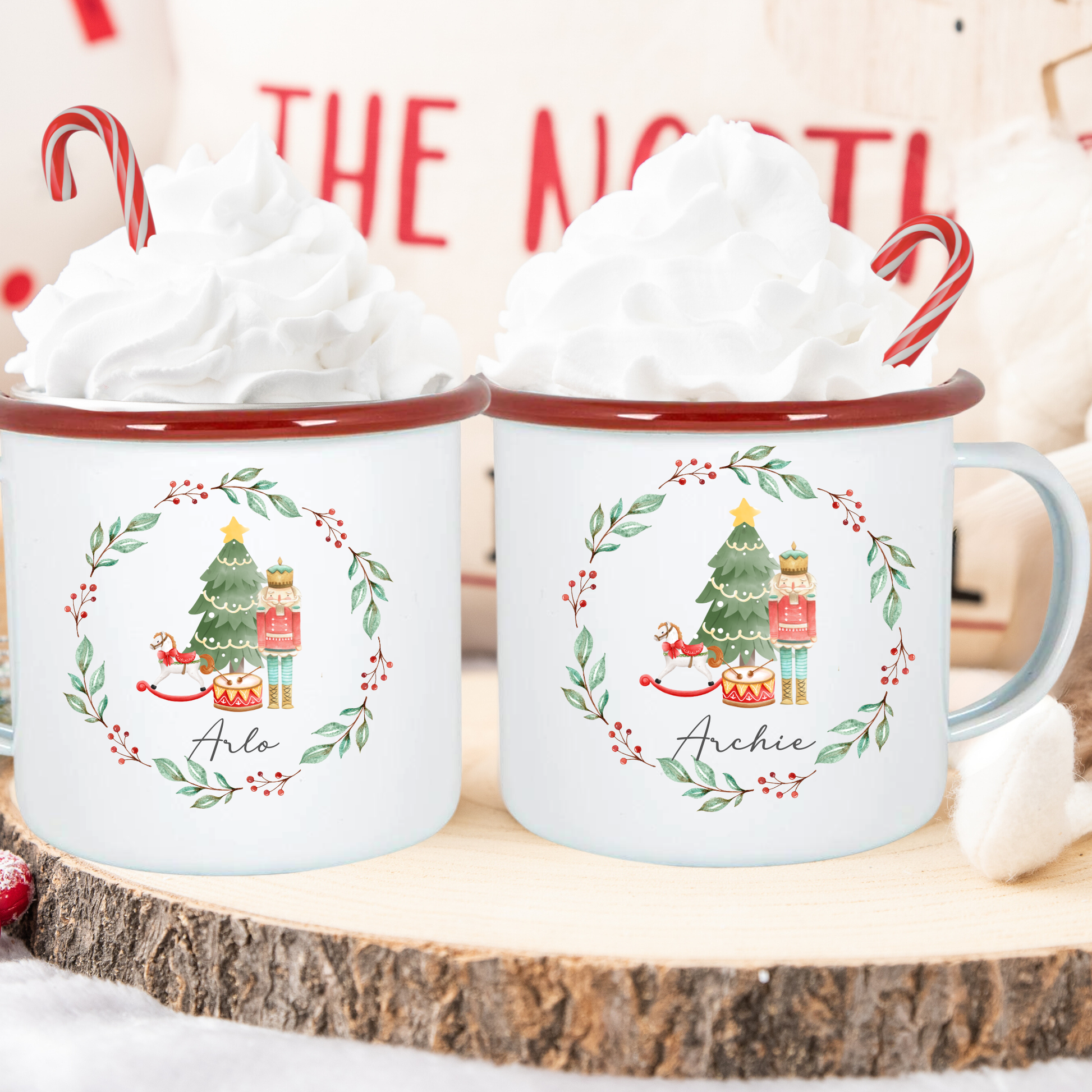 Two Christmas-themed mugs with tree and gift design on a wooden surface.