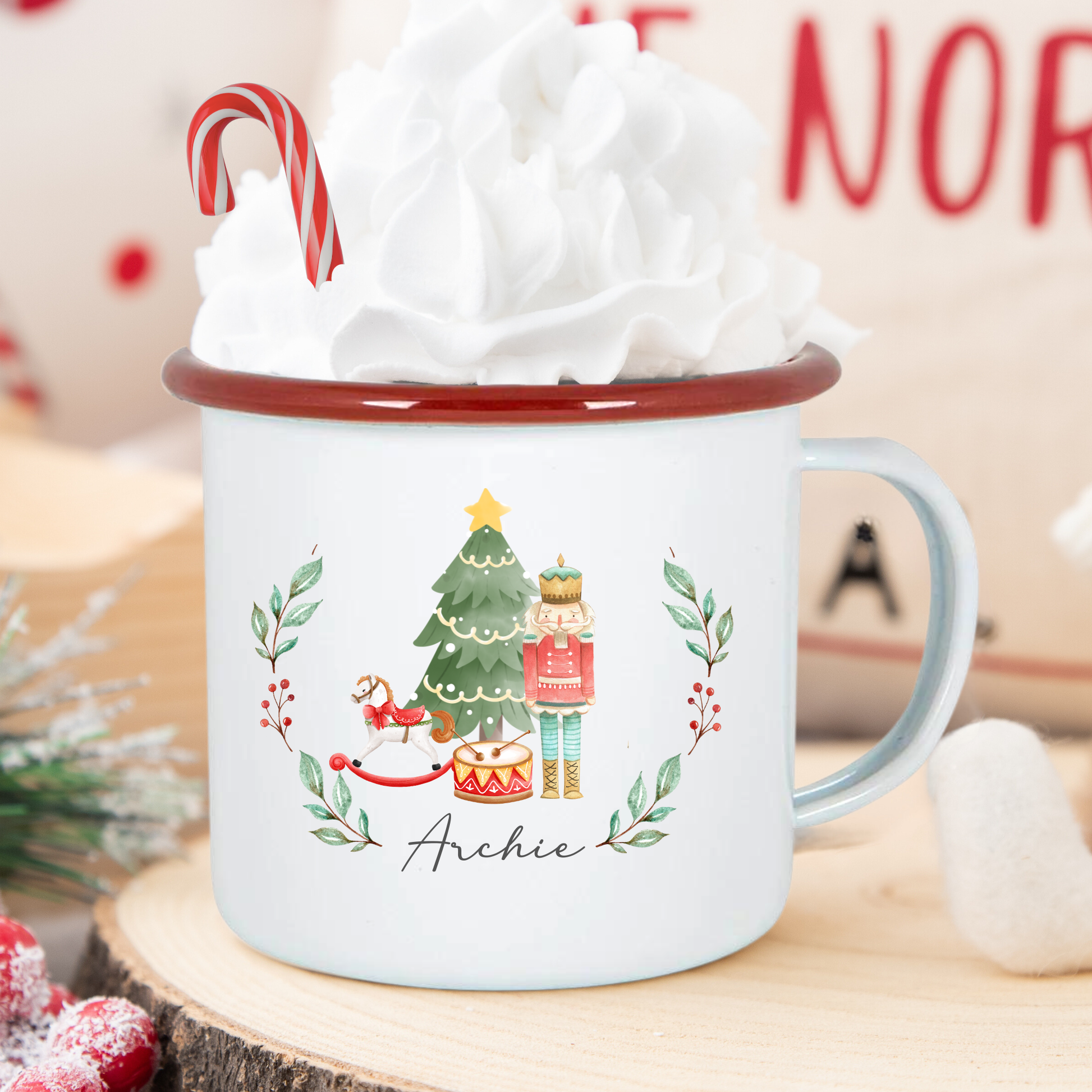 Christmas-themed mug with a tree and candy cane design, filled with hot chocolate and whipped cream.
