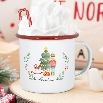 Christmas-themed mug with a tree and candy cane design, filled with hot chocolate and whipped cream.