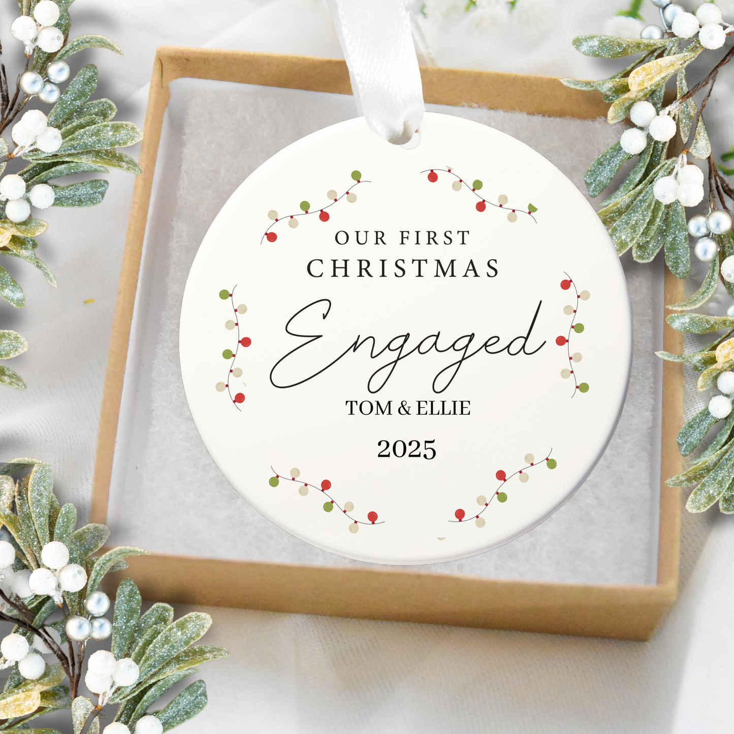 Personalized Christmas ornament with 'Our First Christmas Engaged' text, surrounded by festive greenery.