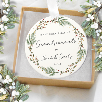Round ornament with text 'First Christmas as Grandparents to Jack & Emily 2004' surrounded by festive greenery.