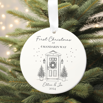 Round Christmas ornament with a door and tree design, hanging on a tree.