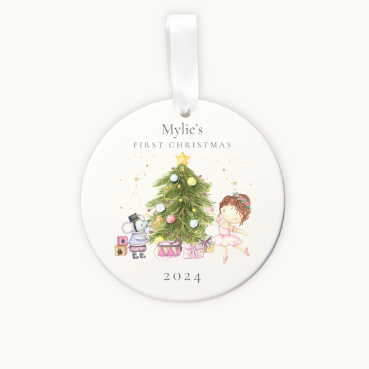 Round Christmas ornament with a child, tree, and snowman design, personalized for 'Mylie's First Christmas 2024'.