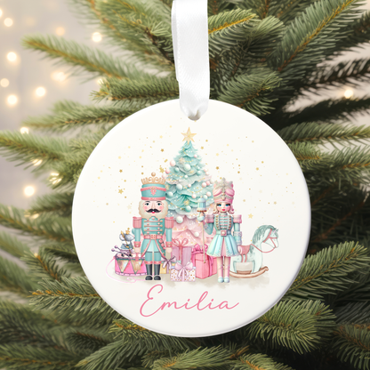 Round Christmas ornament with Nutcracker design and 'Emilia' text, hanging on a tree.