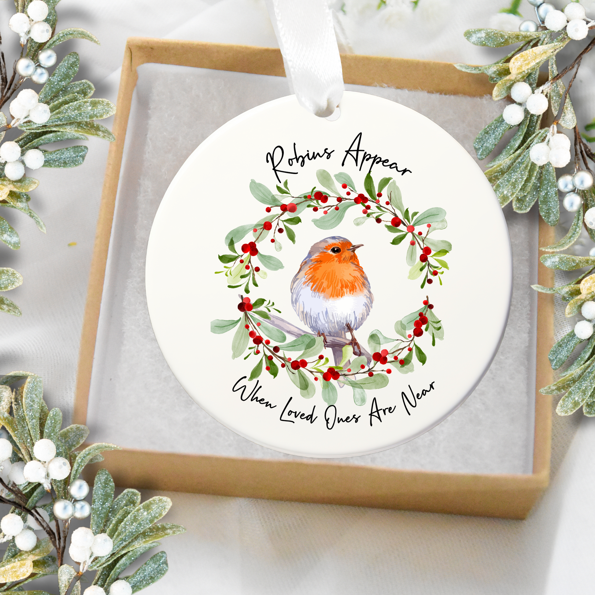 Round Christmas ornament with a robin and wreath design, surrounded by festive greenery.