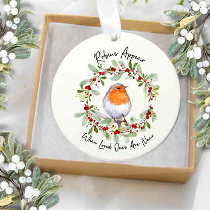 Round Christmas ornament with a robin and wreath design, surrounded by festive greenery.