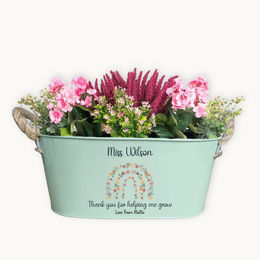 Decorative planter with flowers and personalized text on a white background