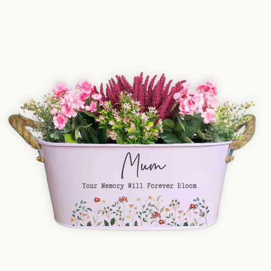 Pink personalised metal garden planter, filled with pretty pink flowers and printed with the words, Mum Your memory will forever bloom. Decorated with delicate uv printed flowers