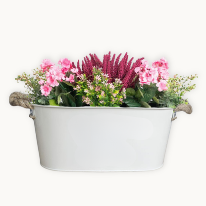 Decorative pebble colour metal planter with flowers on a white background