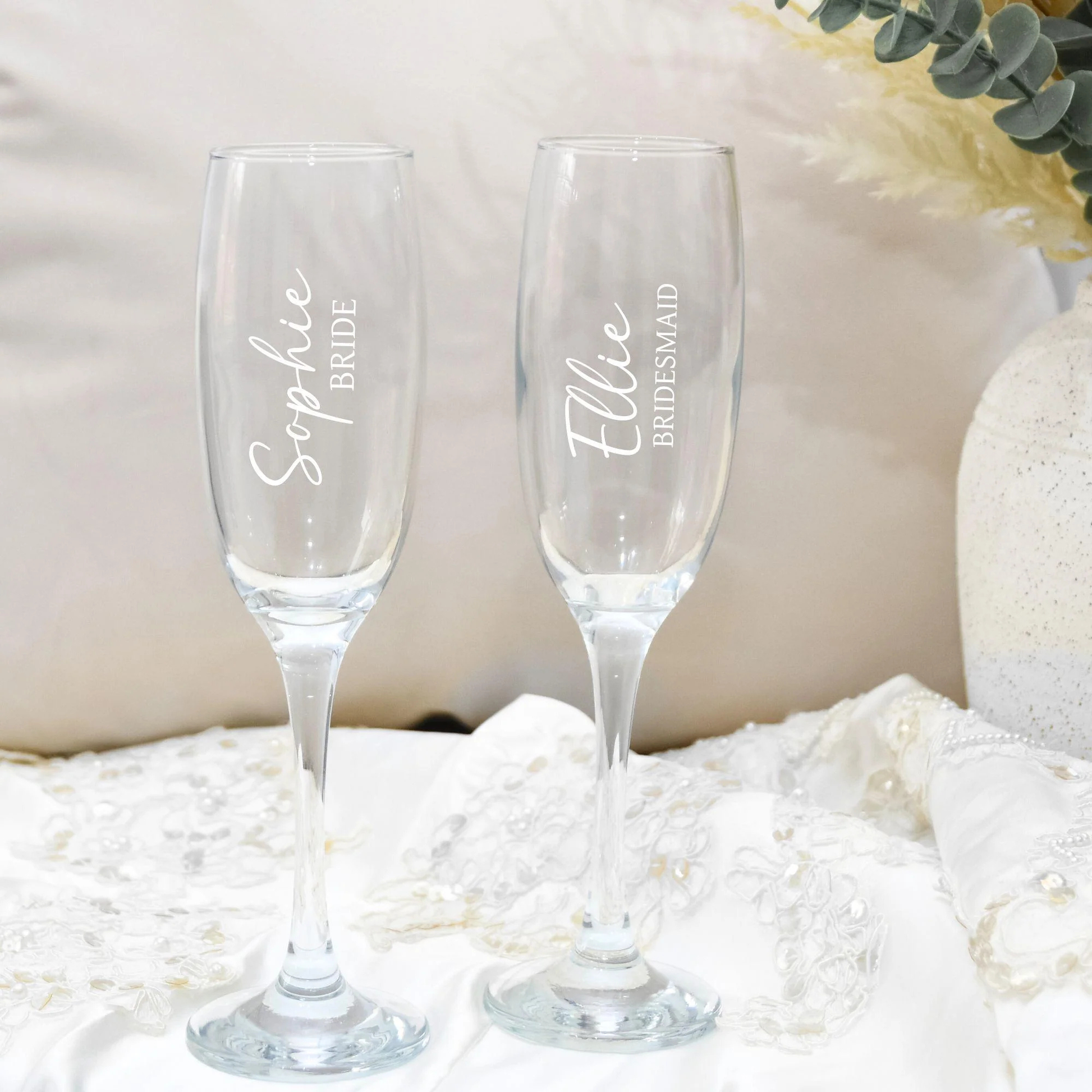 Two champagne flutes with personalized names on a soft white background