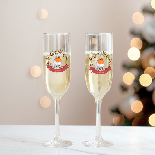 Two champagne flutes with Christmas-themed design on a blurred festive background