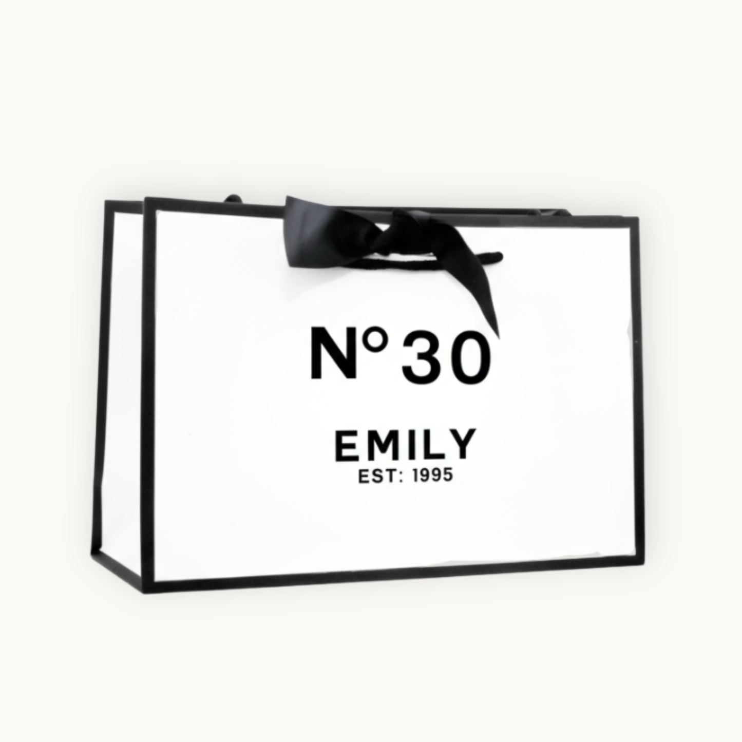 Luxury white gift bag with black border and black ribbon tied in a bow. Printed with the words No 30 Emily est: 1985 on a clean white bacground