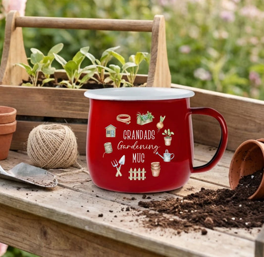 Gardening tools and a red mug on a wooden table with flowers in the background