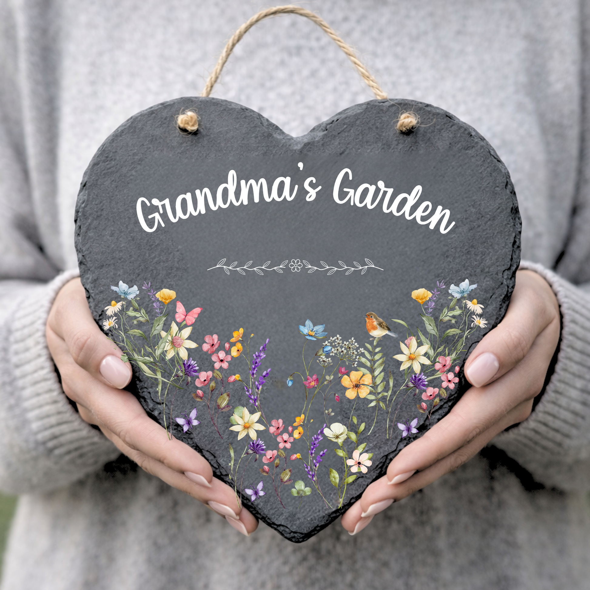 Heart-shaped slate sign with floral design and 'Grandma's Garden' text held by a person.