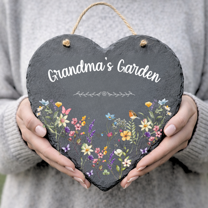 Heart-shaped slate sign with floral design and 'Grandma's Garden' text held by a person.