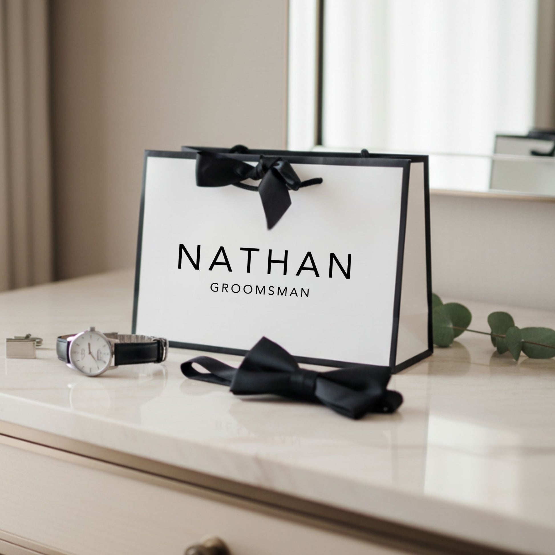 Groomsmen gift bag with 'Nathan Groomsman' text on a marble surface with accessories.