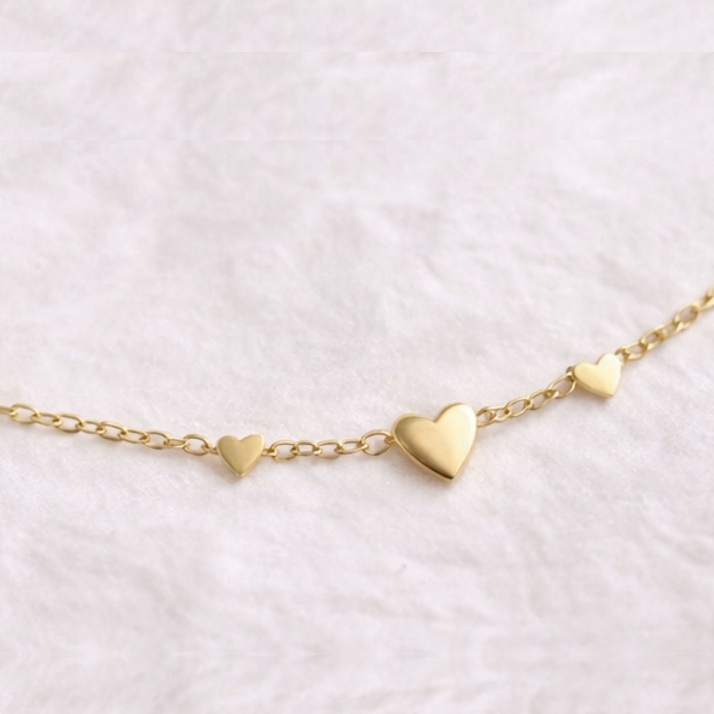 Gold heart-shaped bracelet on a light pink background