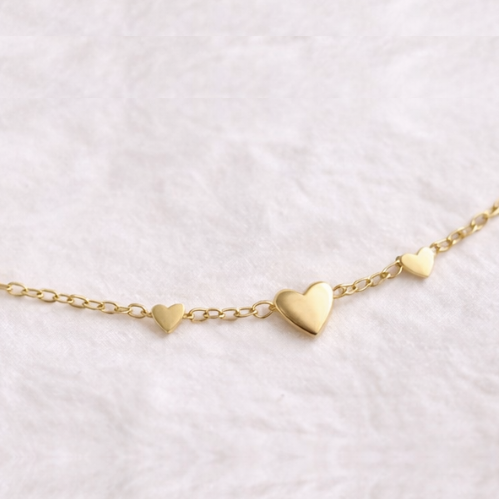 Gold heart-shaped bracelet on a light pink background
