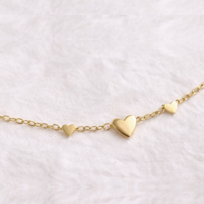 Gold heart-shaped bracelet on a light pink background
