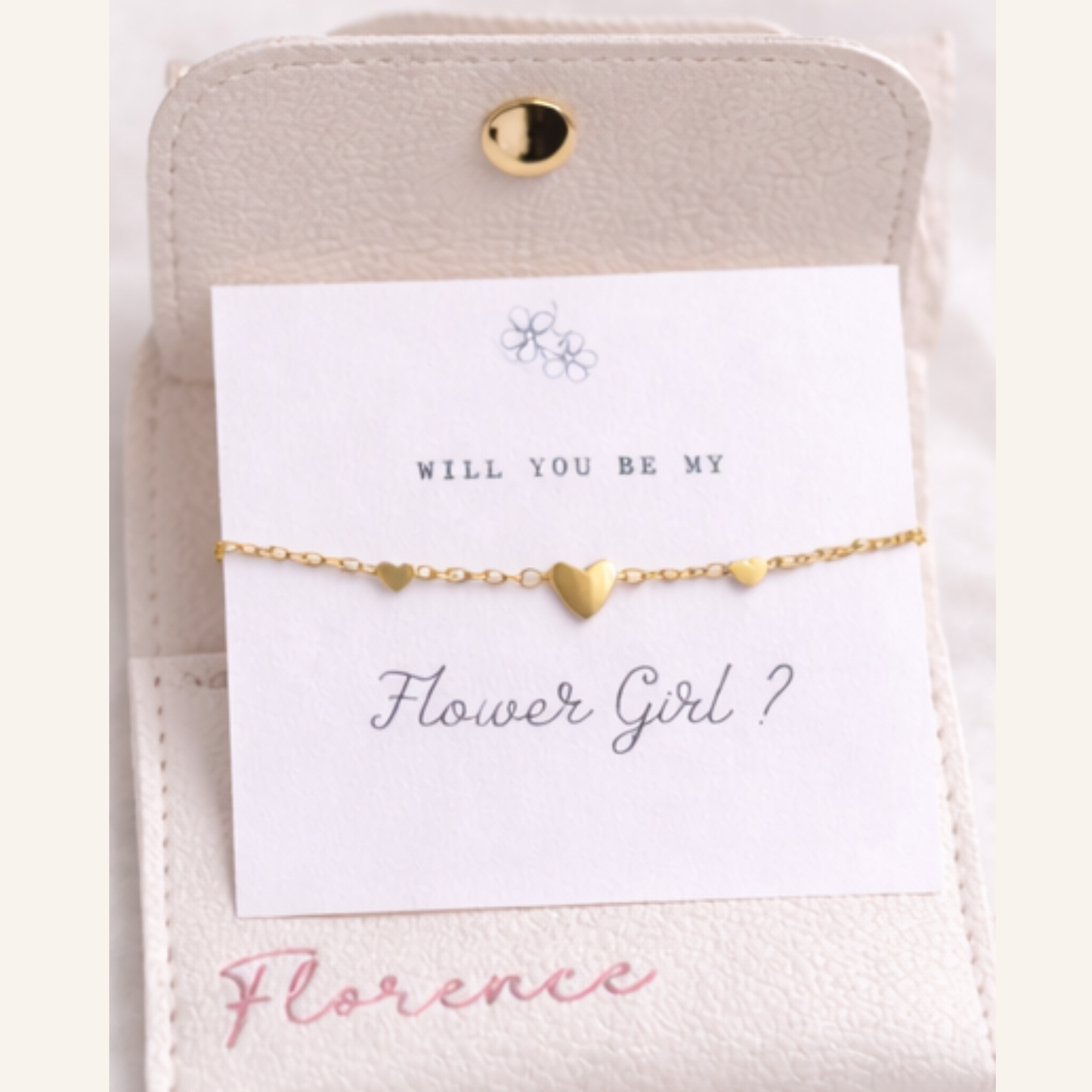 Gold heart bracelet on a card with 'Will you be my Flower Girl?' text, on a light background
