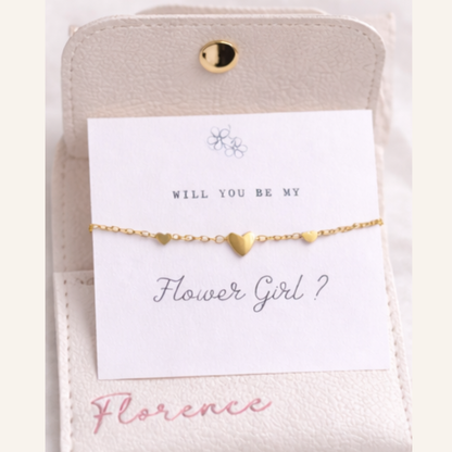 Gold heart bracelet on a card with 'Will you be my Flower Girl?' text, on a light background