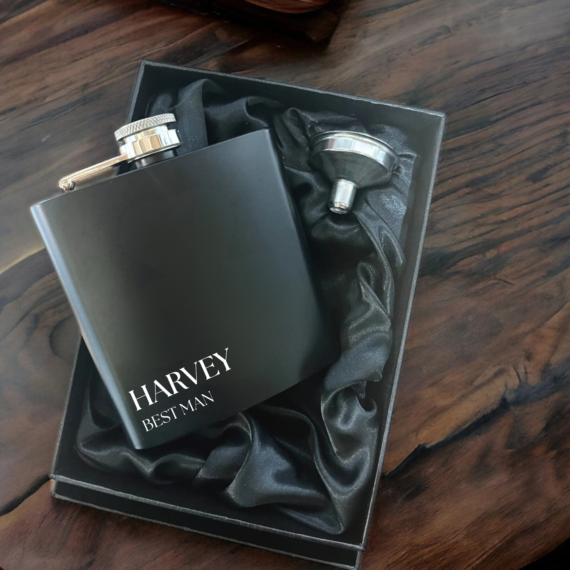 Black flask with 'Harvey Best Man' text in a box on a wooden surface
