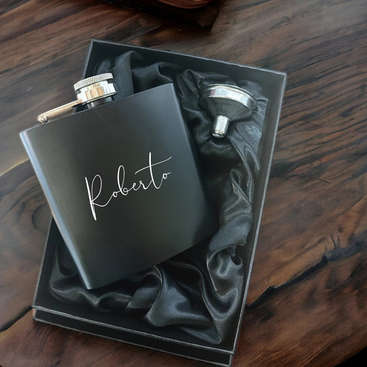 Black flask with 'Roberto' engraving in a box on a wooden surface