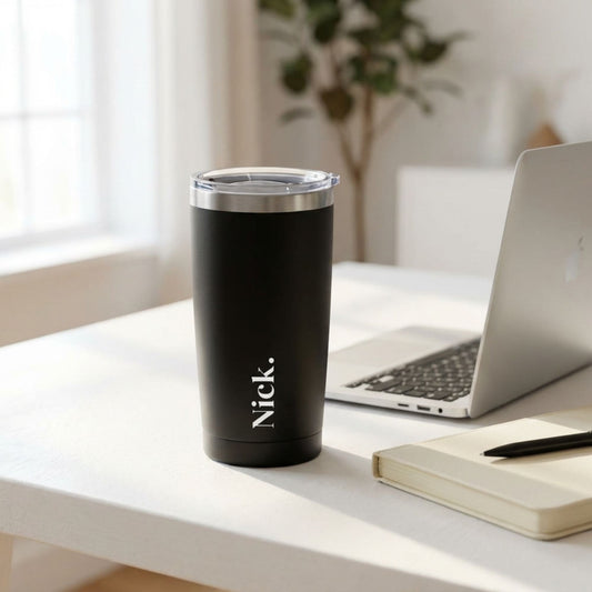 Black tumbler with 'Nick' branding on a desk with a laptop and notebook.