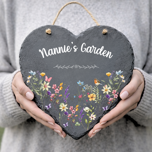 Heart-shaped slate sign with floral design and 'Nannie's Garden' text held by a person.