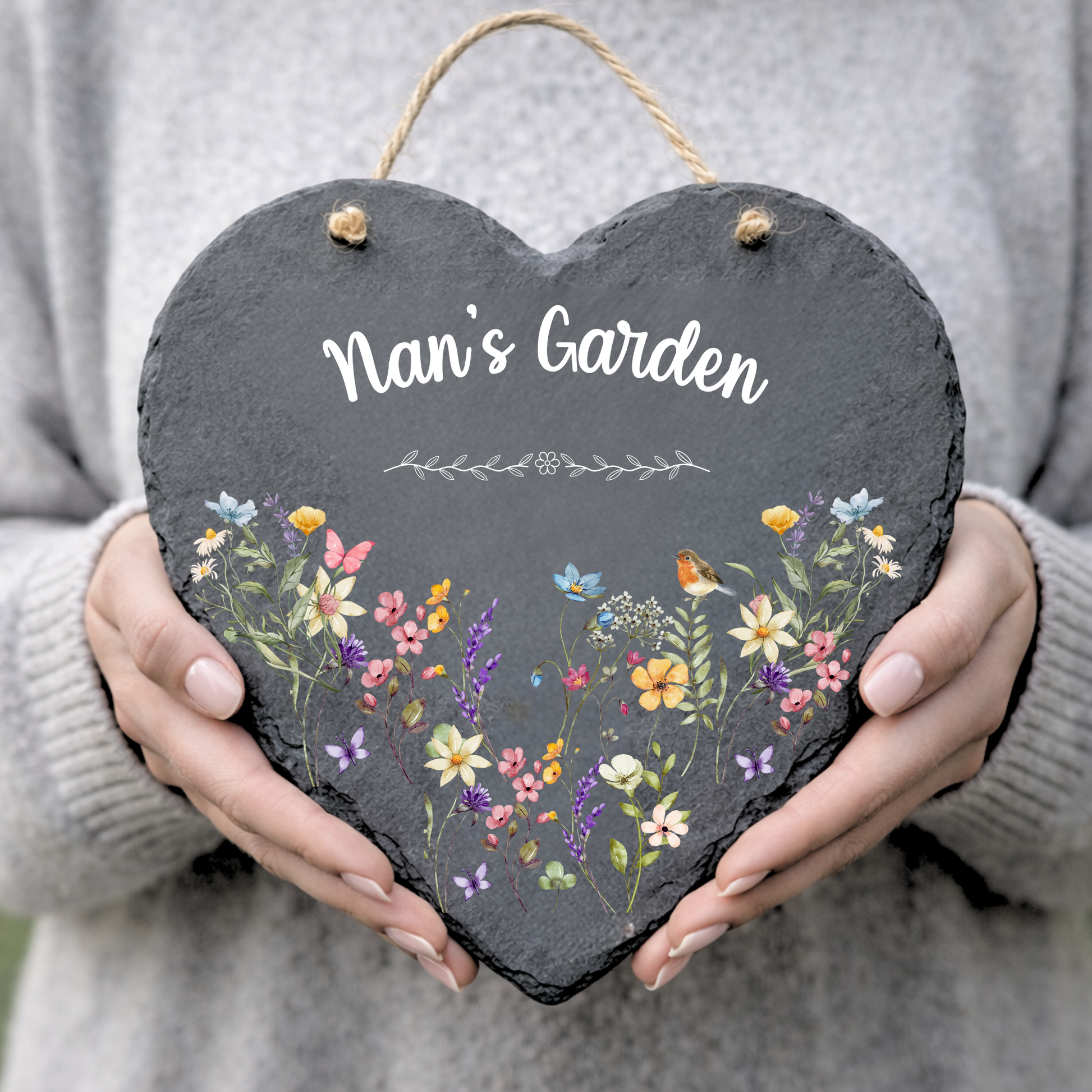 Heart-shaped slate sign with floral design and 'Nan's Garden' text held by a person.