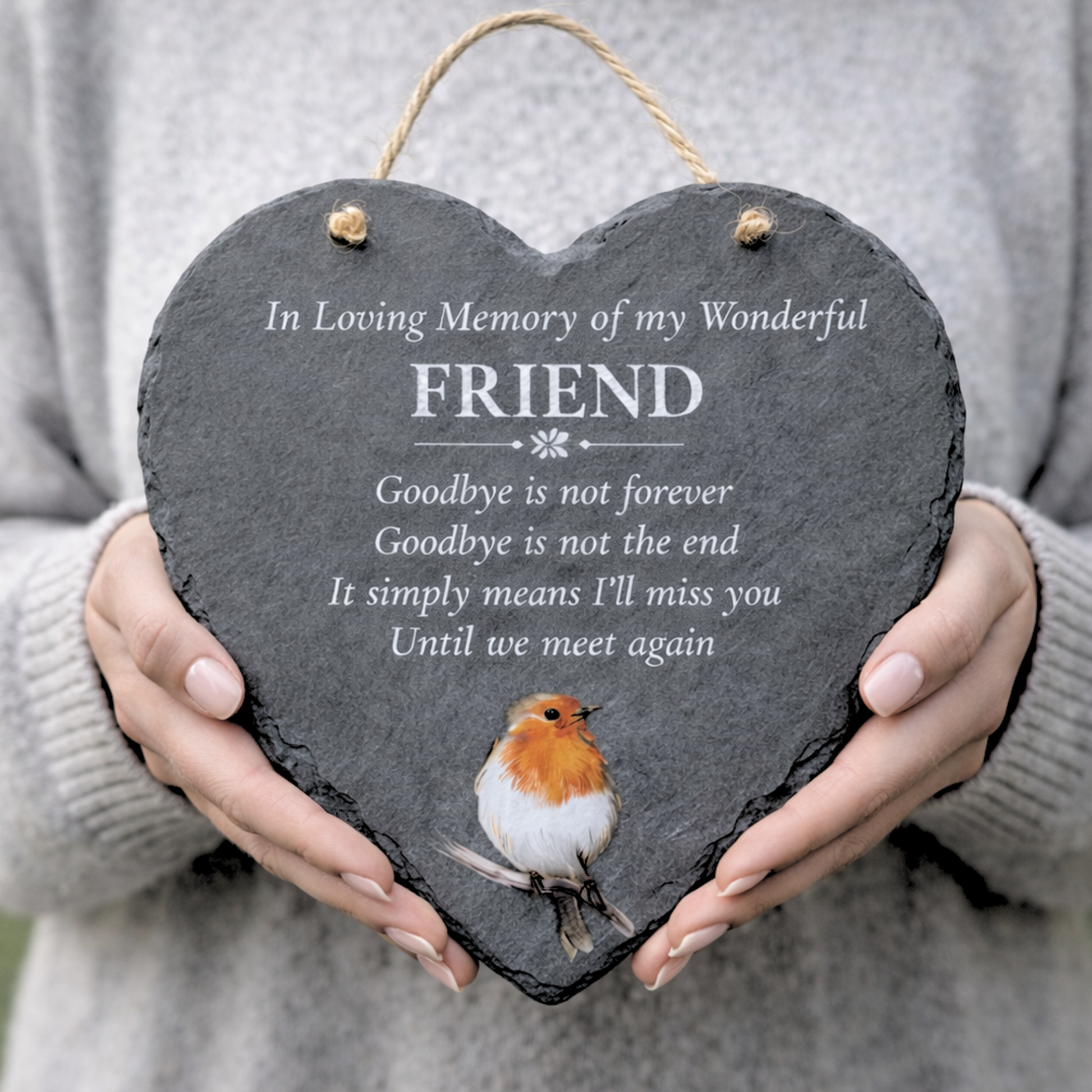 Heart-shaped slate plaque with a robin illustration and memorial text, held by a person.