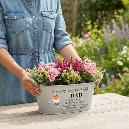 A woman holding a grey memorial planter printed with in memory of my wonderful Dad with a robin illustration, with a garden background