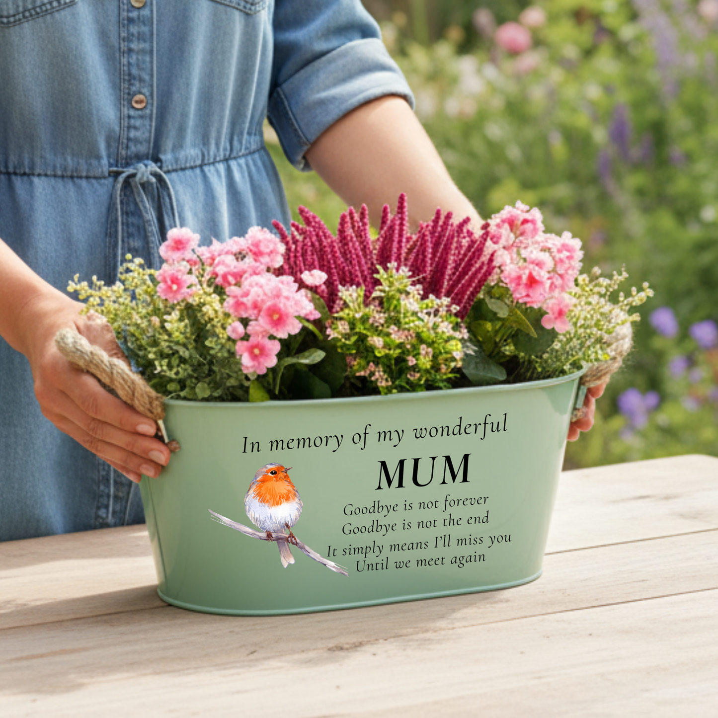 A woman holding Sage green memorial planter printed with in memory of my wonderful mum with a robin illustration, with a garden background