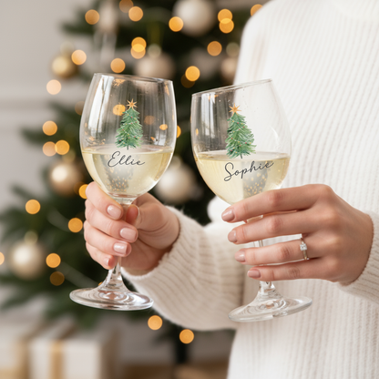 Wine glass with Christmas tree print and personalised name, held in hand