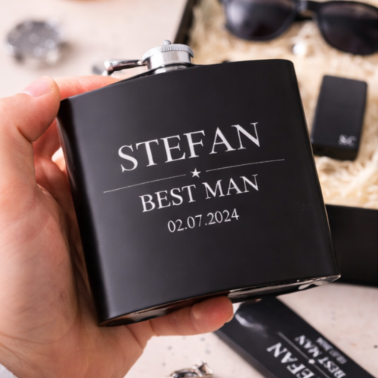 Black flask with 'STEFAN BEST MAN 02.07.2024' text held in a hand.