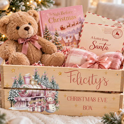 A wooden Christmas Eve gift box labeled 'Felicity's Christmas Eve Box' filled with a brown teddy bear wearing a pink bow, a pink 'The Night Before Christmas' book, a cream 'A Letter from Santa' card, and a pink plaid throw blanket, set against a softly blurred holiday background.