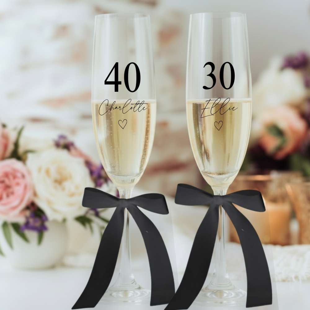 Personalised birthday champagne flutes with age and name printed, elegant bow detail, milestone birthday glass gift.
