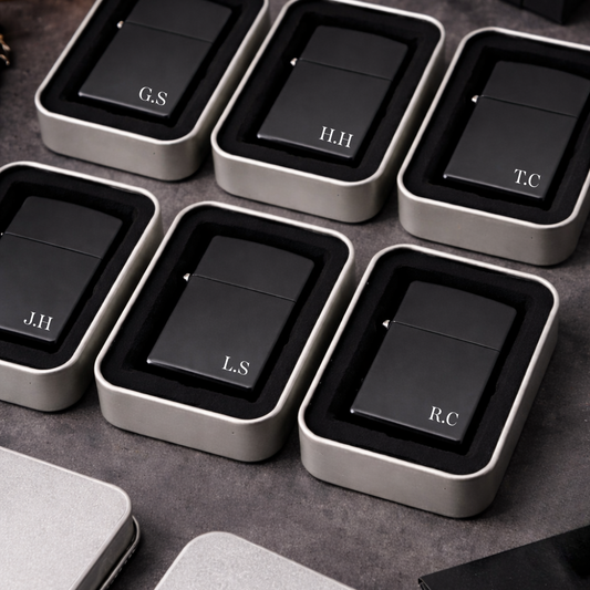 Black lighters with initials in gray cases on a dark surface for groomsman or best man gift