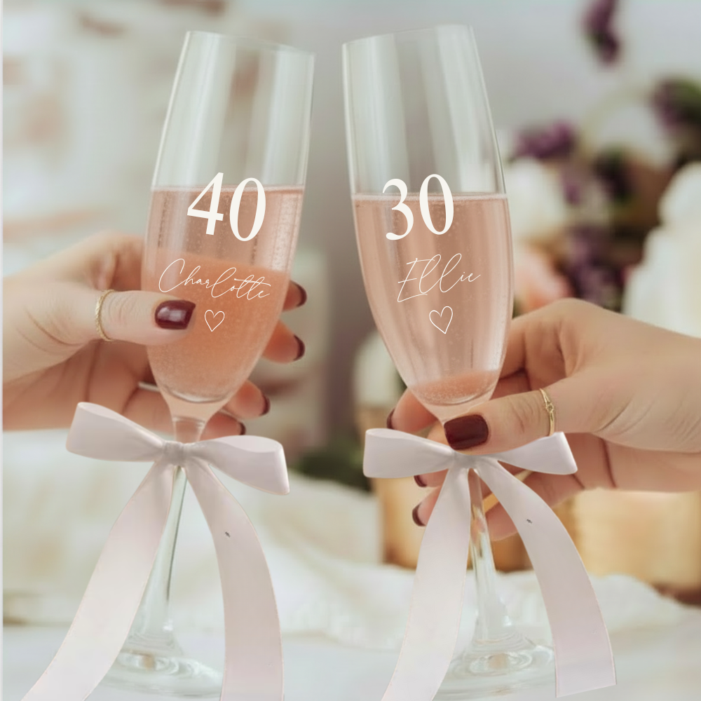 Pair of personalised birthday prosecco flutes being toasted, with name and age printed on each glass